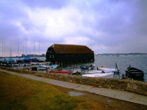 Spring high tide at Bosham harbour. The weatherboarded building is the current Bosham yacht Club and was formerly a tide mill. The area is under the administration of the Bosham Hundred and Manor which dates back to at least 1248.